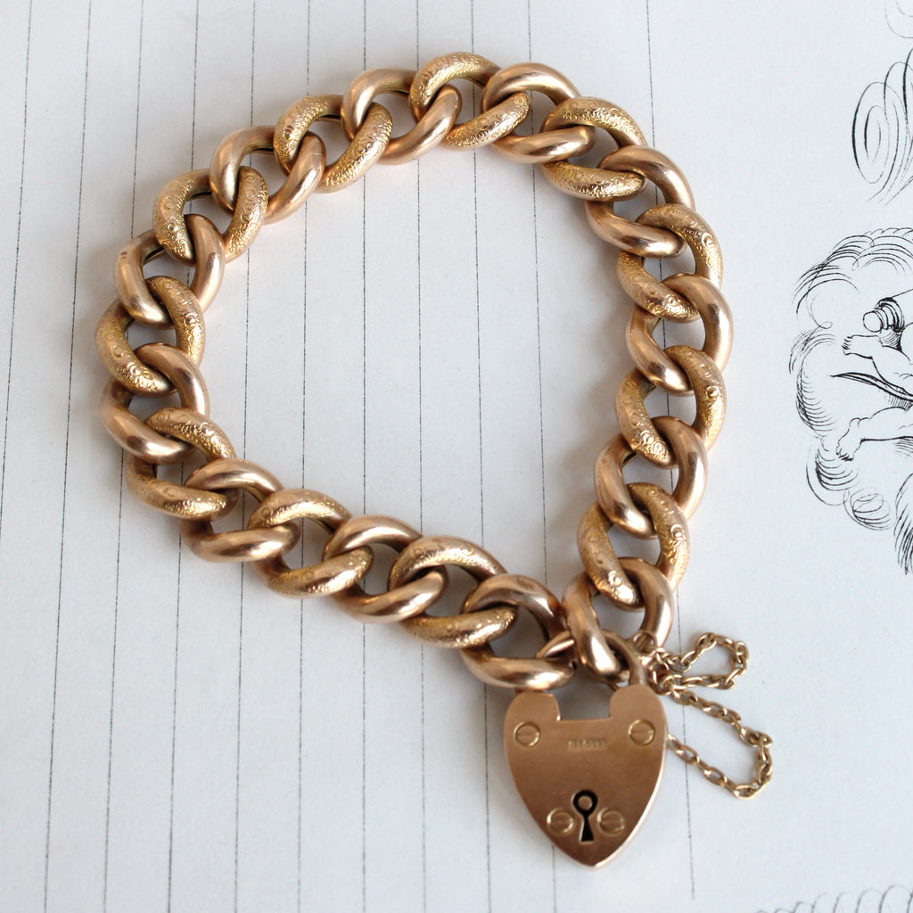 thick curb chain bracelet in yellow gold with a heart shaped padlock clasp