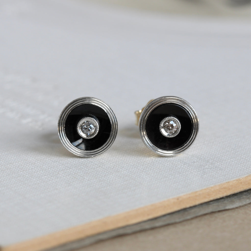 small round stud earrings of black onyx in a white gold bezel and diamonds set in the centers