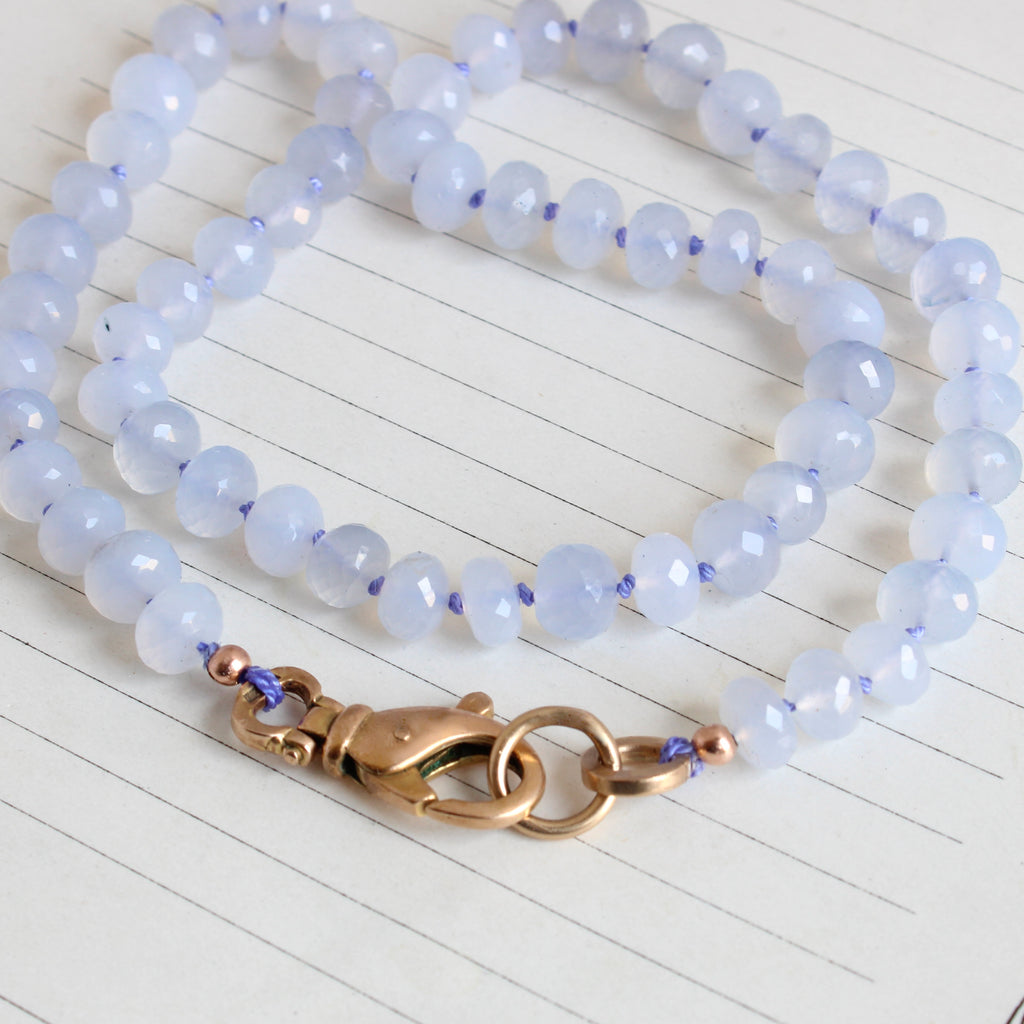 light lavendar faceted chalcedony beads knotted on purple silk with a gold lobster clasp