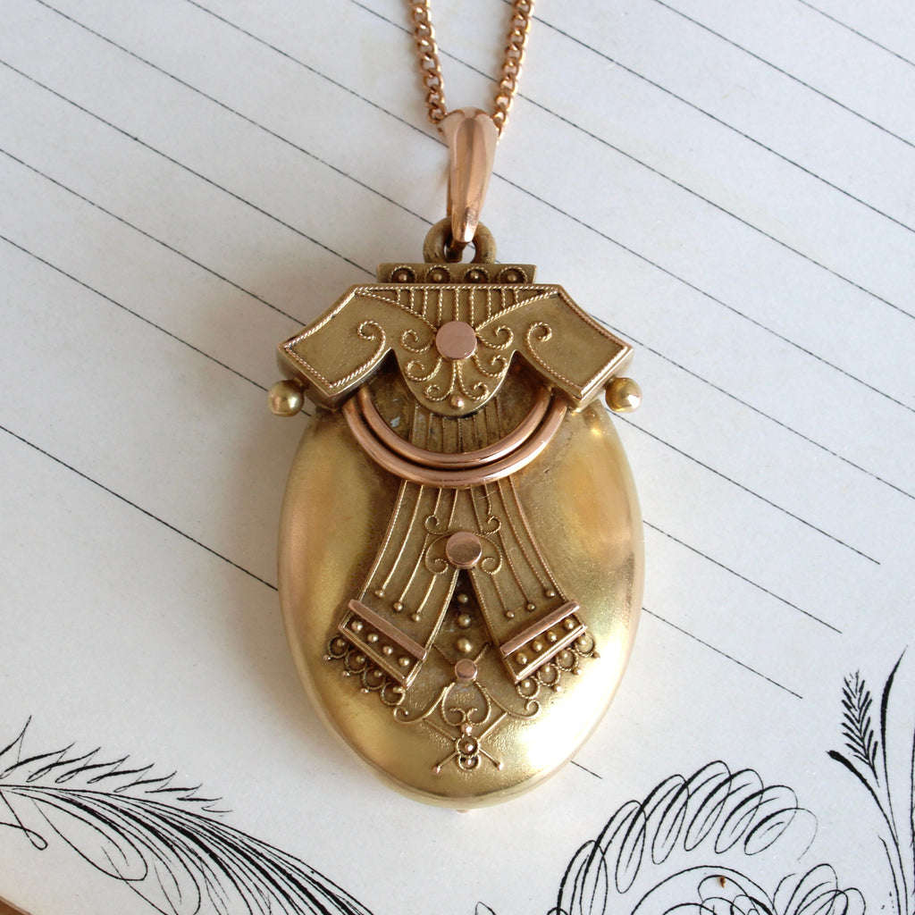 large oval antique gold locket with filigree accents on a gold chain