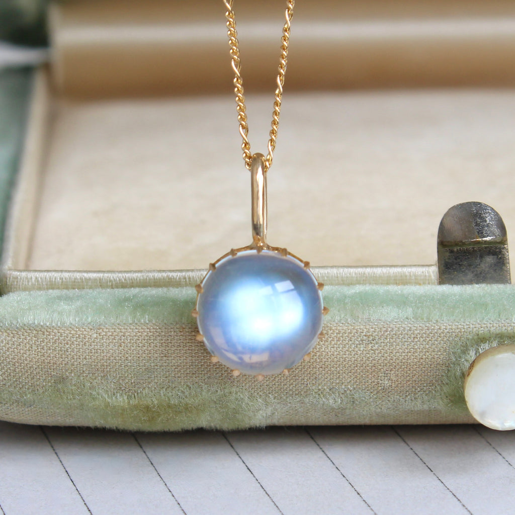 a moonstone cabchon charm in a yellow gold crown setting on a gold chain