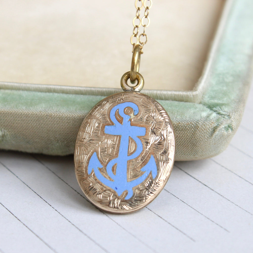 yellow gold metal oval locket with a light blue enamel anchor on the front, on a gold chain