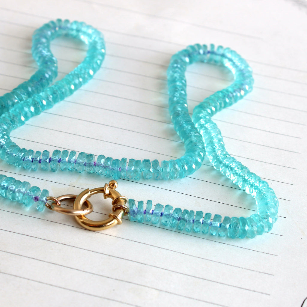 a gemstone bead necklace of bright turquoise blue apatite beads with a round gold clasp