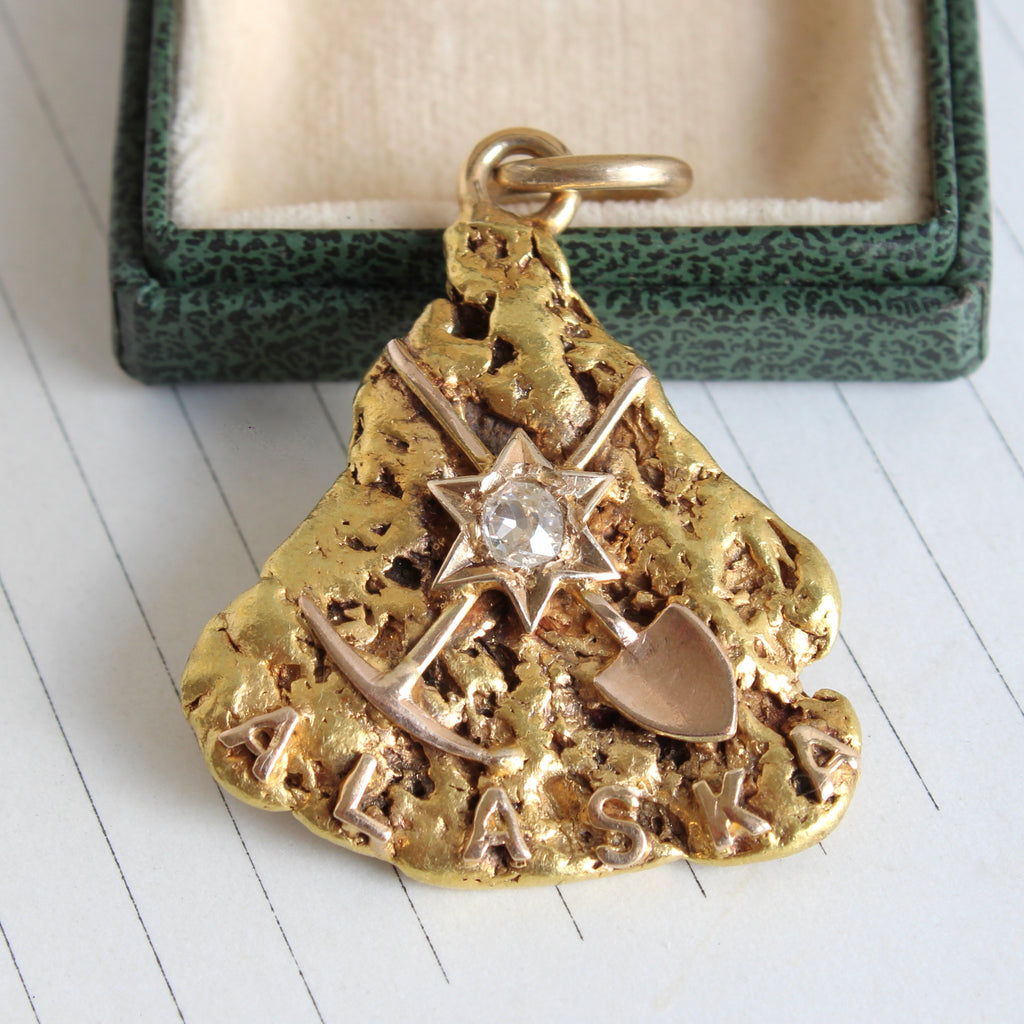 very large natural gold nugget with an applied set of mining tools and a star set with a diamond