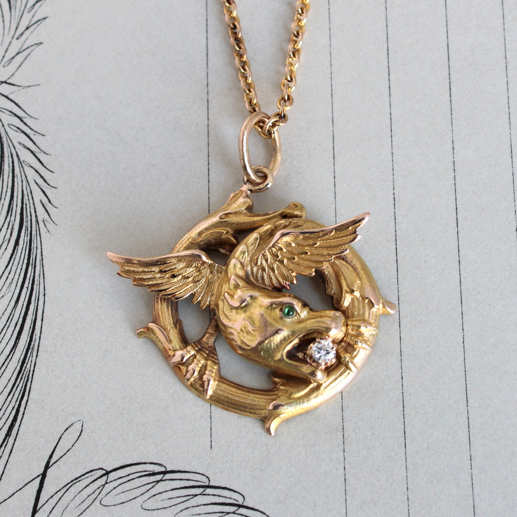 antique yellow gold pendant of a winged dragon holding a diamond in his mouth with a yellow gold chain