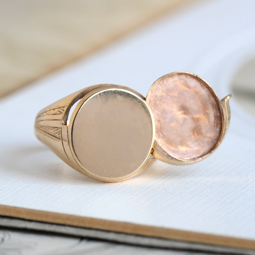vintage yellow gold signet ring with a hidden locket compartment behind the face that can hold a photograph.