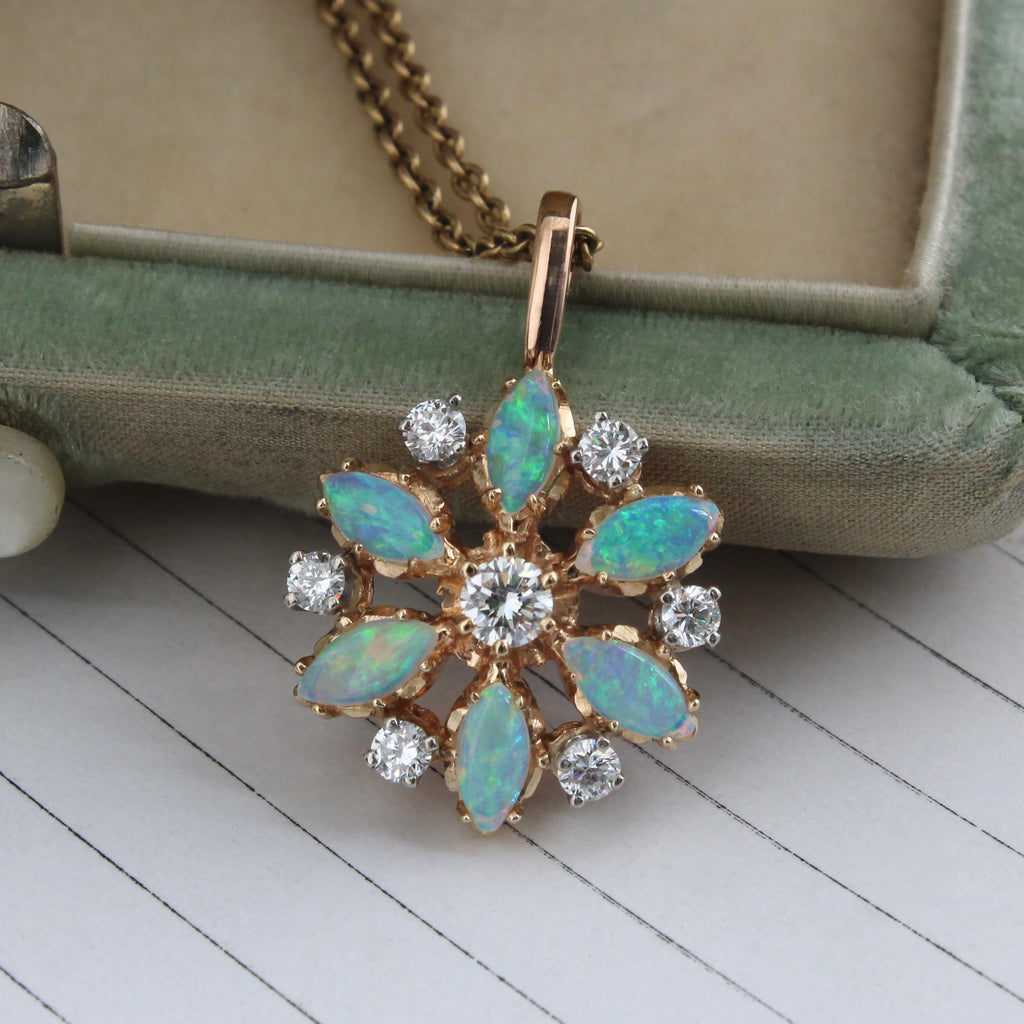 starburst pendant of yellow gold set with six marquise shaped blue green opals and seven diamonds, on a gold chain