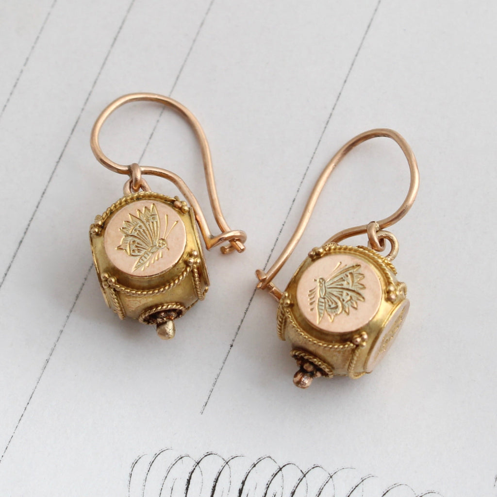 antique gold earrings with a cube shaped drop that has butterflies engraved on all sides