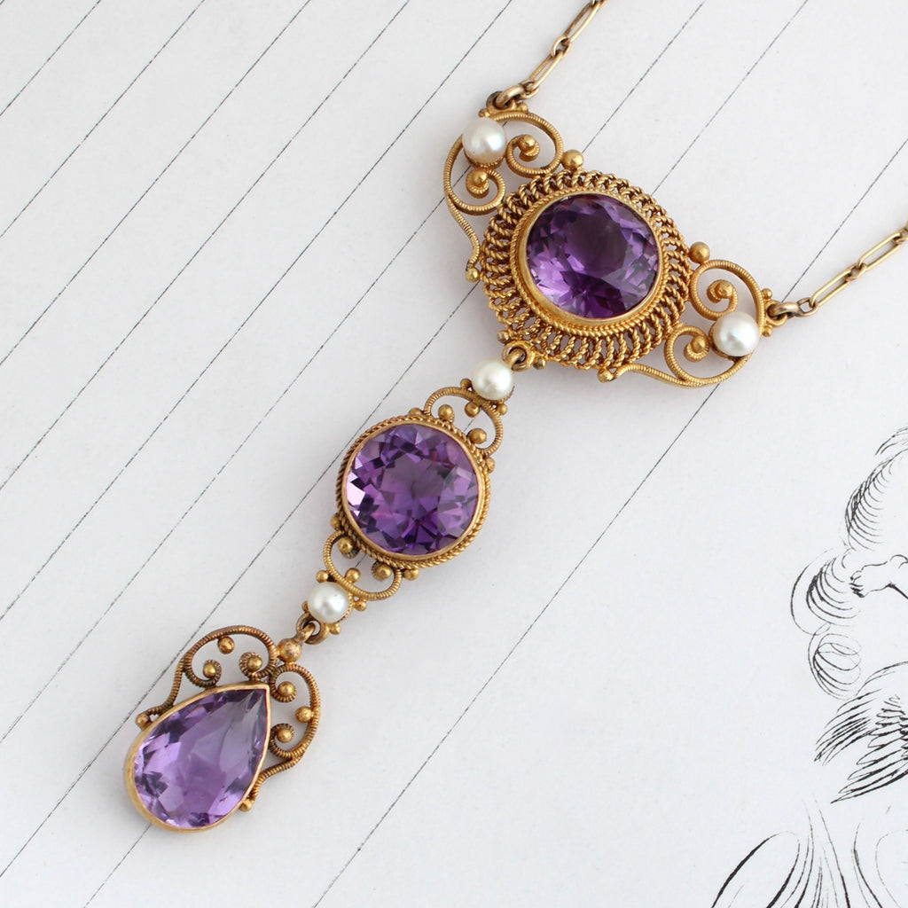 yellow gold necklace with filigree stations in a drop arrangement for three deep purple amethyst accented by pearls