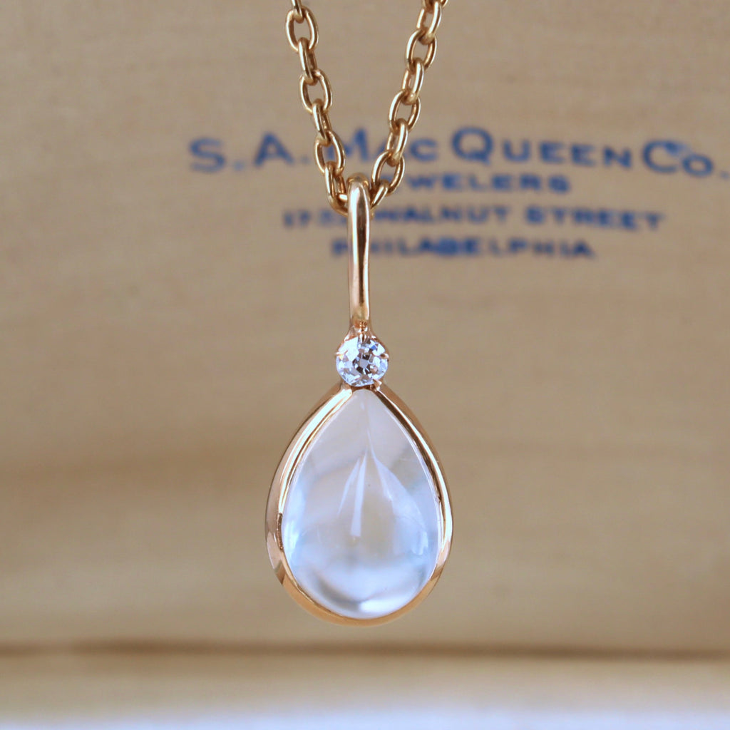 teardrop cabochon moonstone pendant in a gold bezel setting with a diamond accent on a gold chain