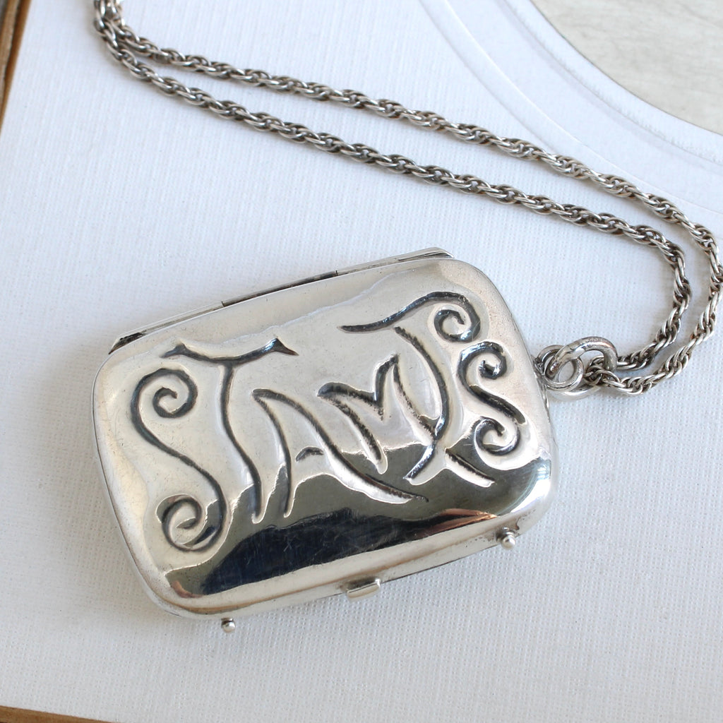 little sterling silver box embossed with the word stamps on a silver chain