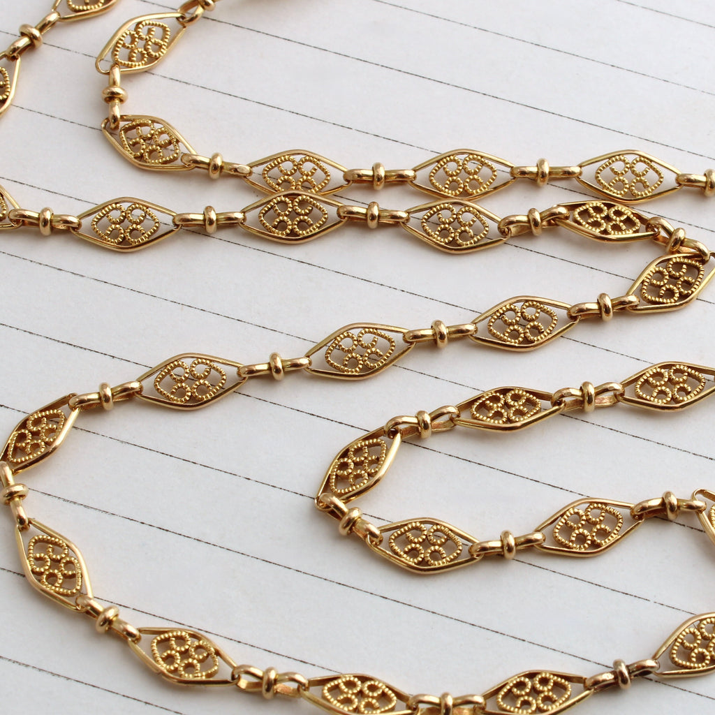 antique yellow gold chain made of diamond shaped links that have filigree details