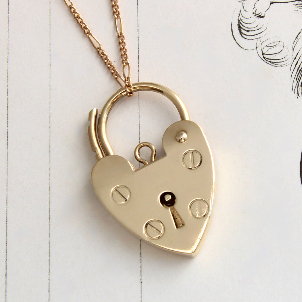 yellow gold padlock in the shape of a heart that opens and closes by means of a curved rod like a handle at the top