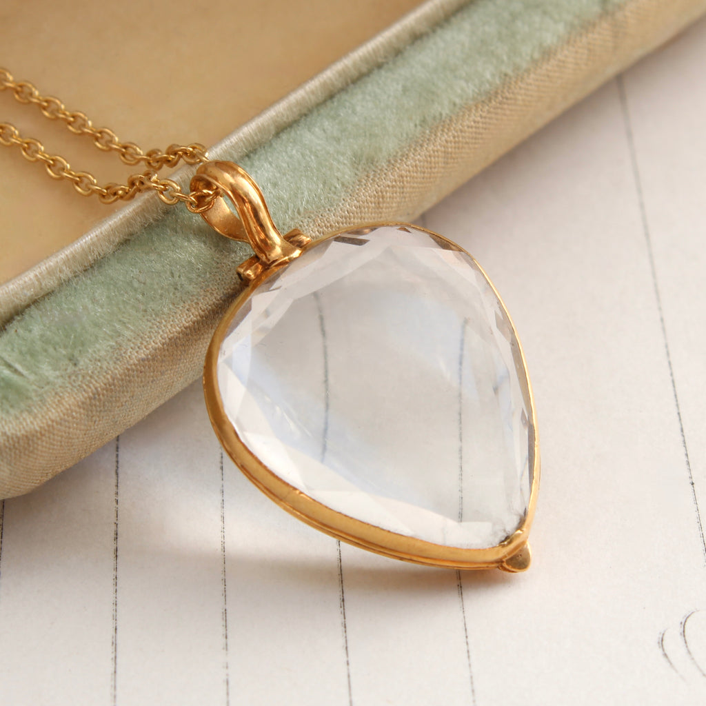 heart shaped locket with front and back faceted clear crystal covers so you can see inside on a gold chain