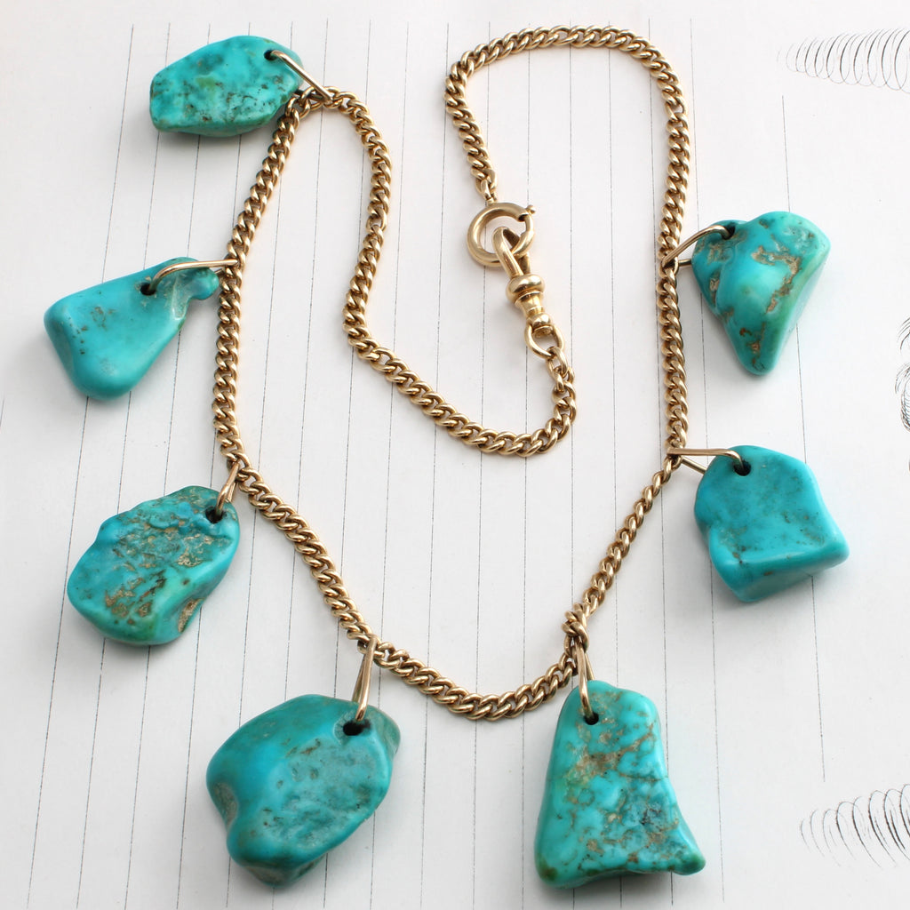 yellow gold curb chain necklace with irregular shaped and large bright turquoise stone drops added