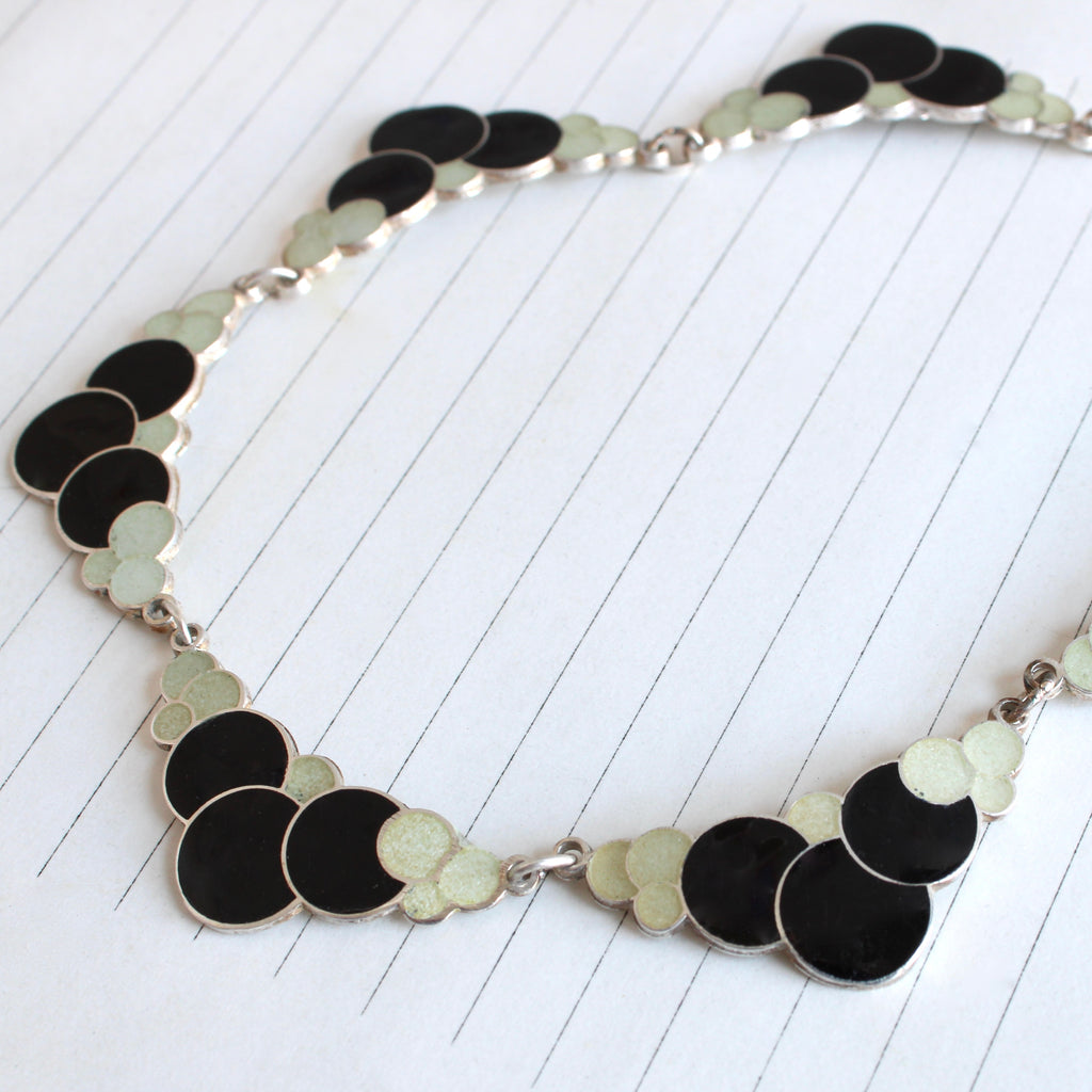 silver necklace made of six plaques designed as enameled bubbles in black and white