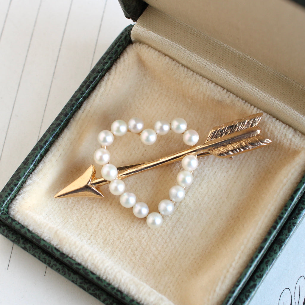 gold brooch designed as a pearl heart with a gold arrow shot through it