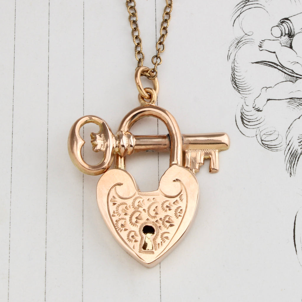 antique yellow gold pendant designed to look like a heart shaped padlock with a key, on a chain