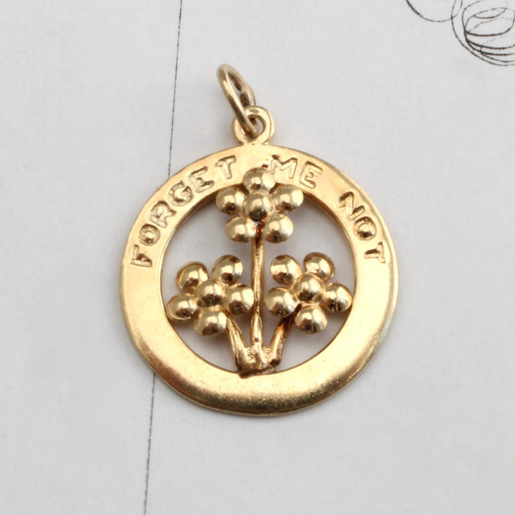 round yellow gold charm with a bouquet of little flowers and the message Forget me not engraved around the top border