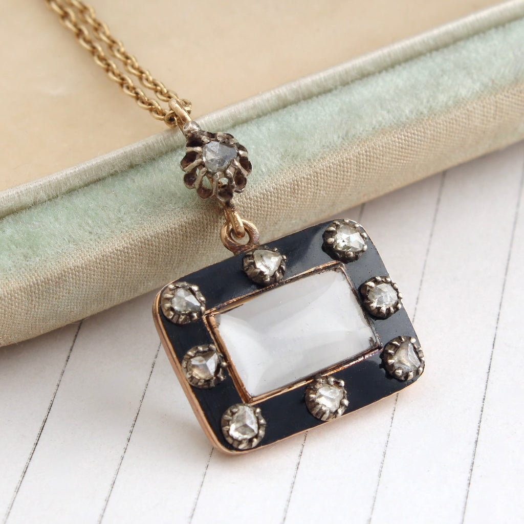 small rectangular antique locket with a black enamel border and rose cut diamonds set within the border on a gold chain