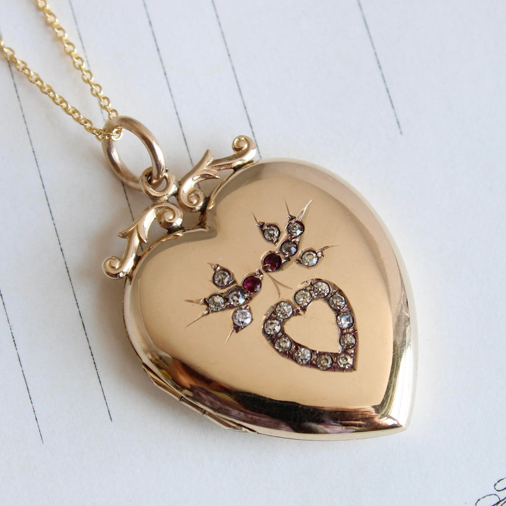 yellow gold heart locket with a pair of birds on the cover flying above a little heart all outlined in rhinestones