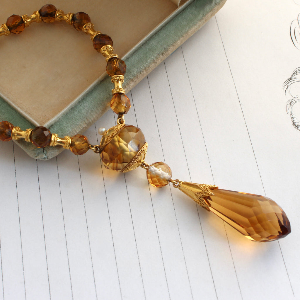 yellow faceted gem beads with high karat gold spacers and a large faceted tear drop shaped pendant capped with gold