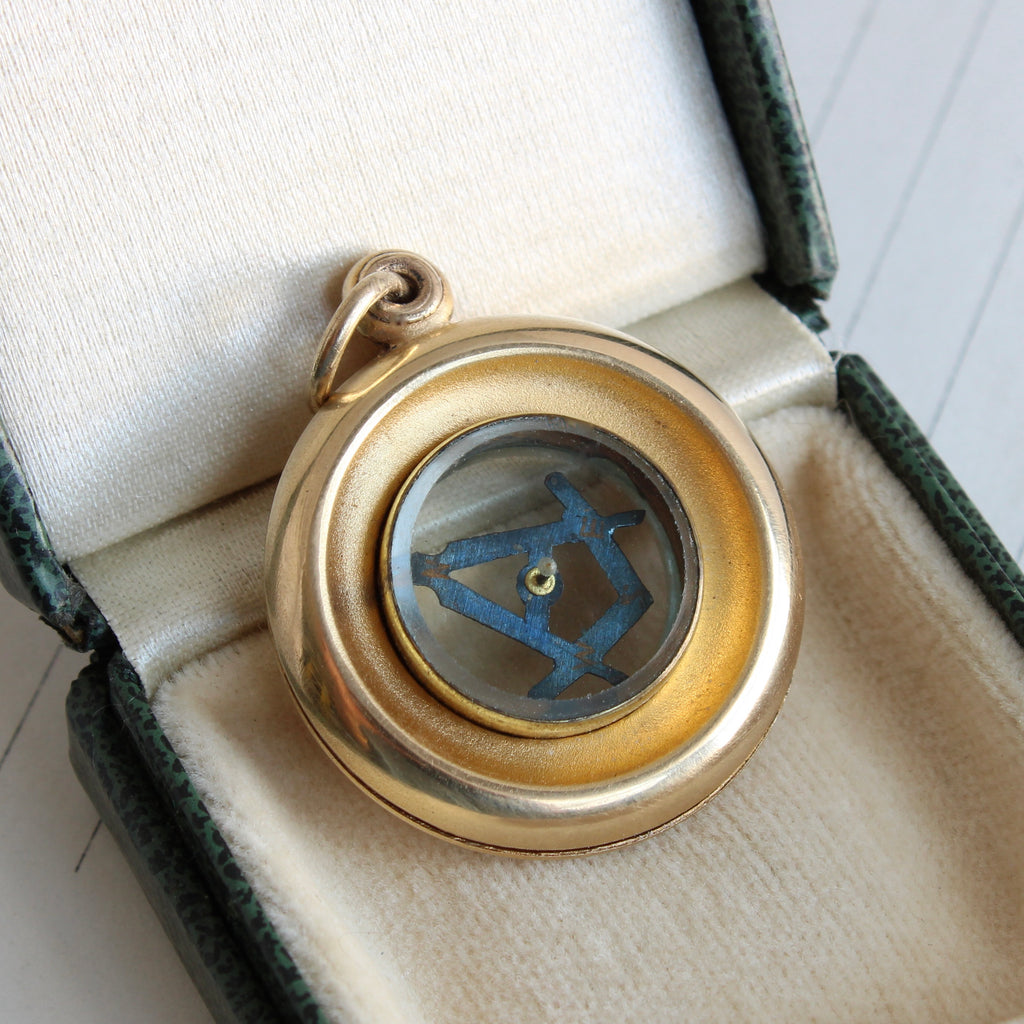 yellow gold colored miniature compass with a masonic symbol as the direction of travel arrow