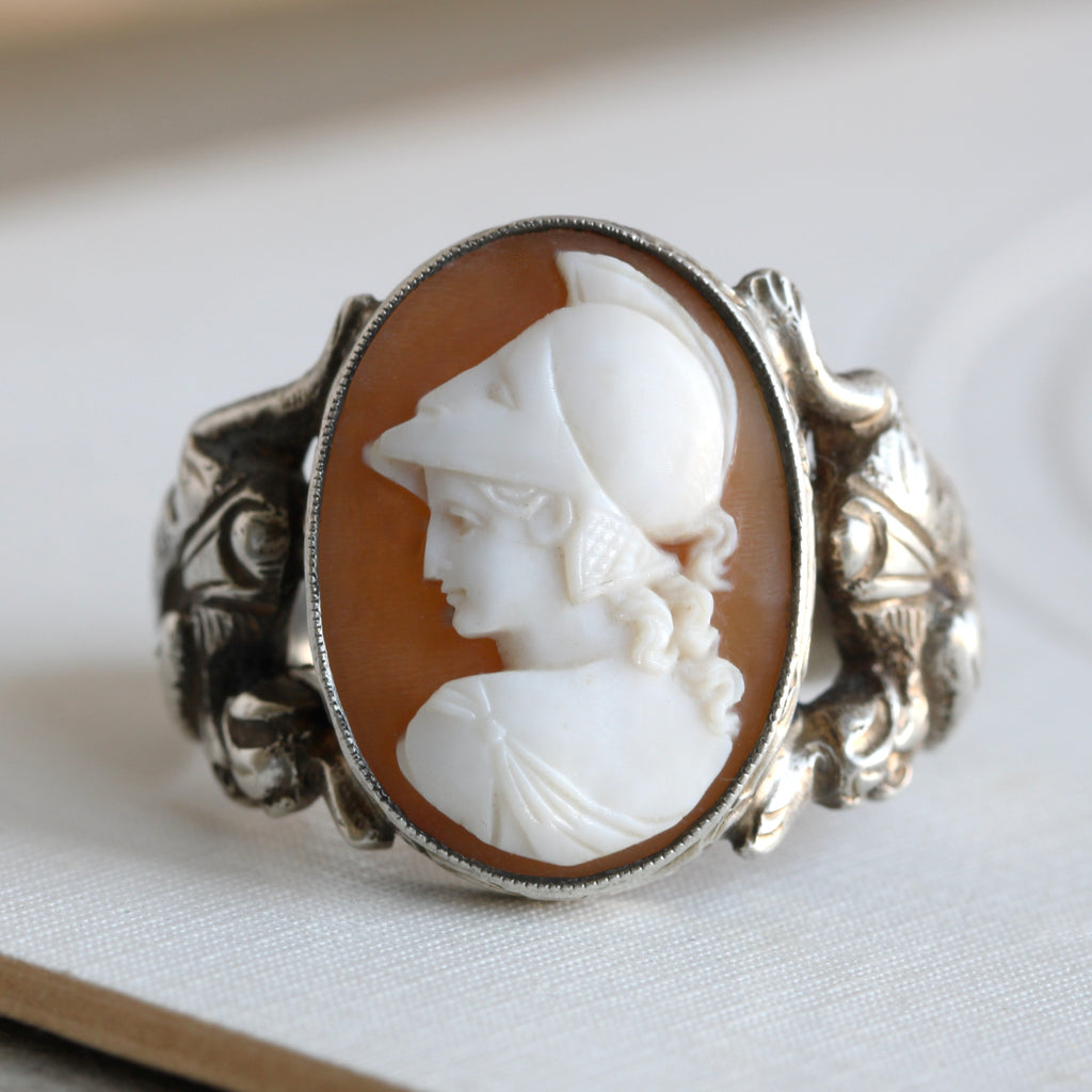 silver ring with shell cameo of goddess athena in a war helmet with heavily carved dragons on the shoulder