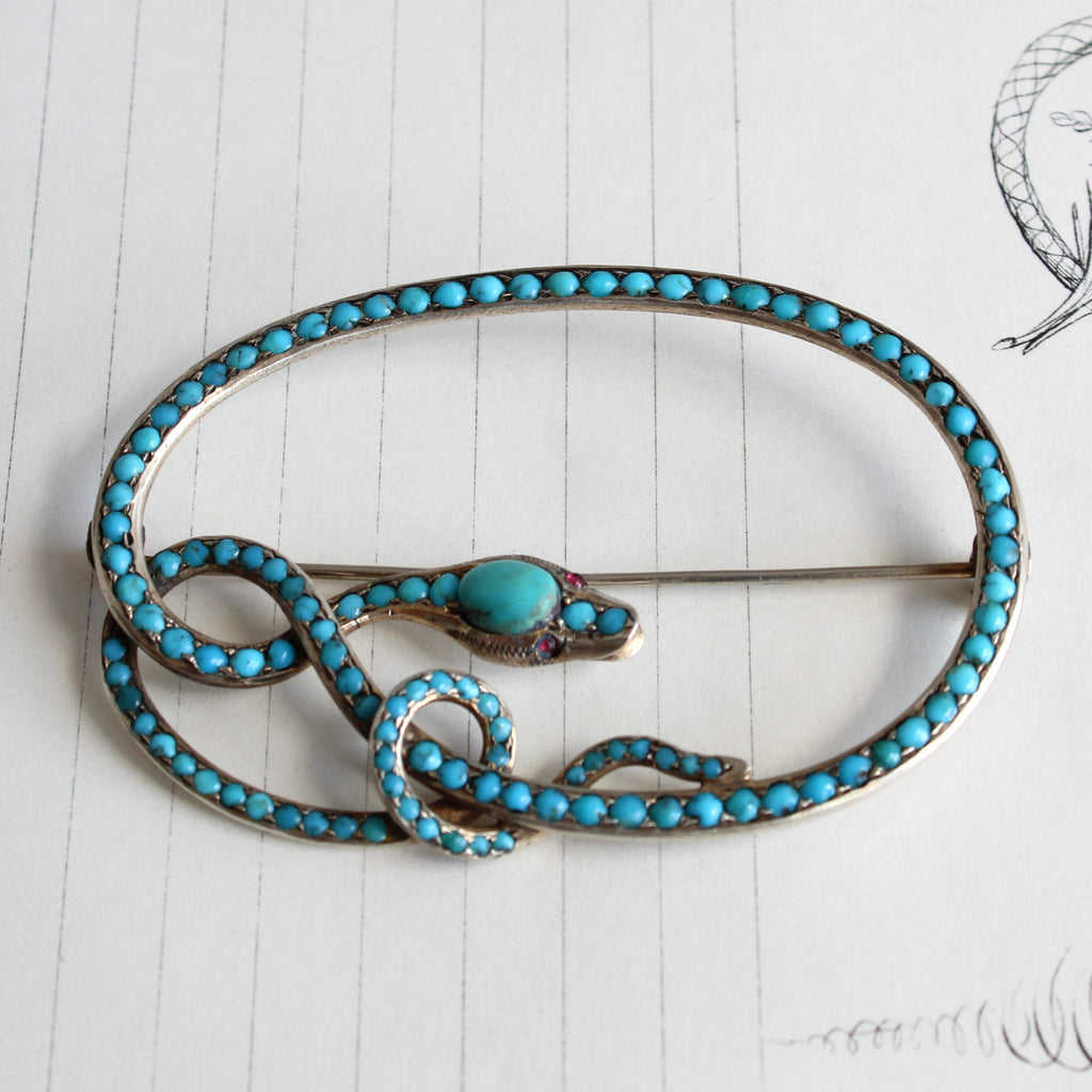 silver coiled snake brooch set with small turquoise cabochons