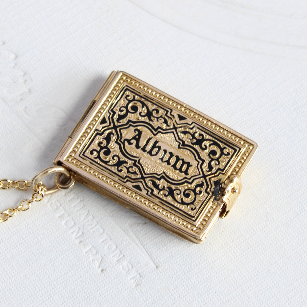 yellow gold book style locket with the word album on the cover that opens to show space for six photos on small pages