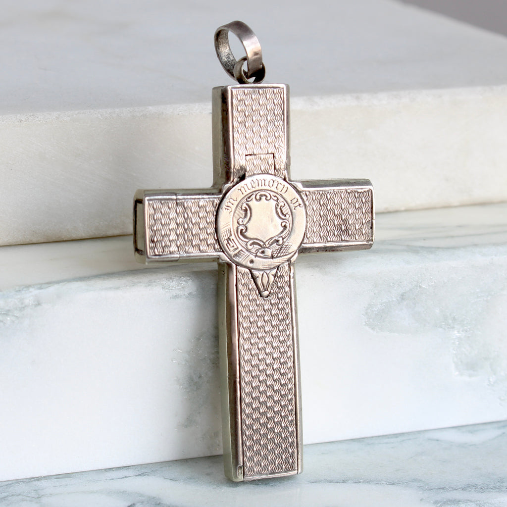 a silver cross locket engraved in memory of on a compartment lid that pops open when the button is pushed  to show an interior compartment