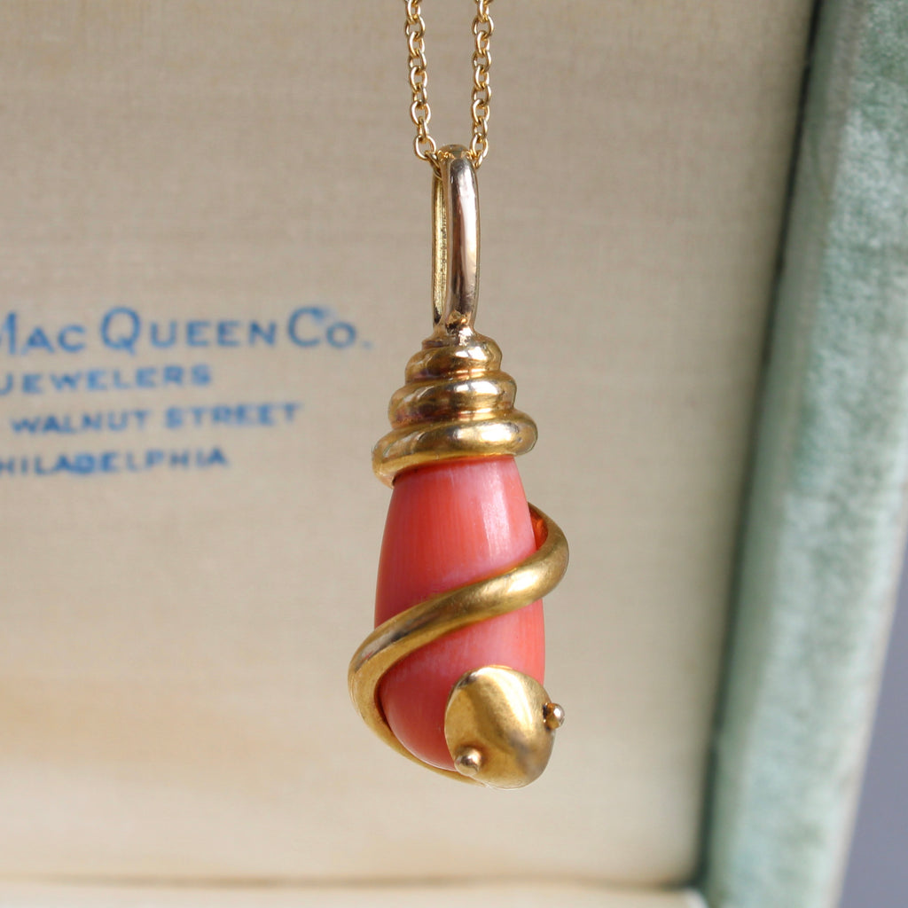 pendant designed as gold snake coiled around a coral teardrop, hung on a gold chain