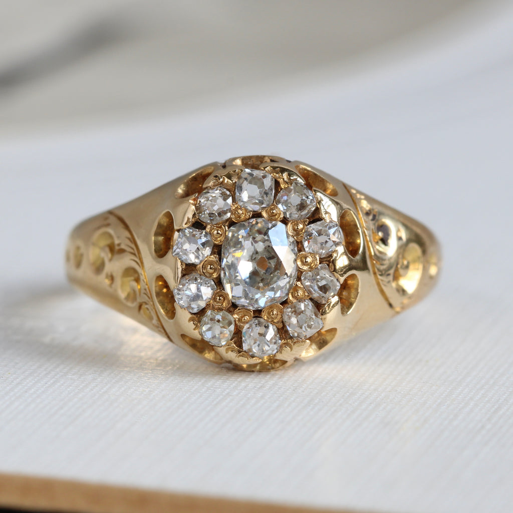 yellow gold ring with an old mine cut diamond in the center of a halo of smaller mine cut diamonds