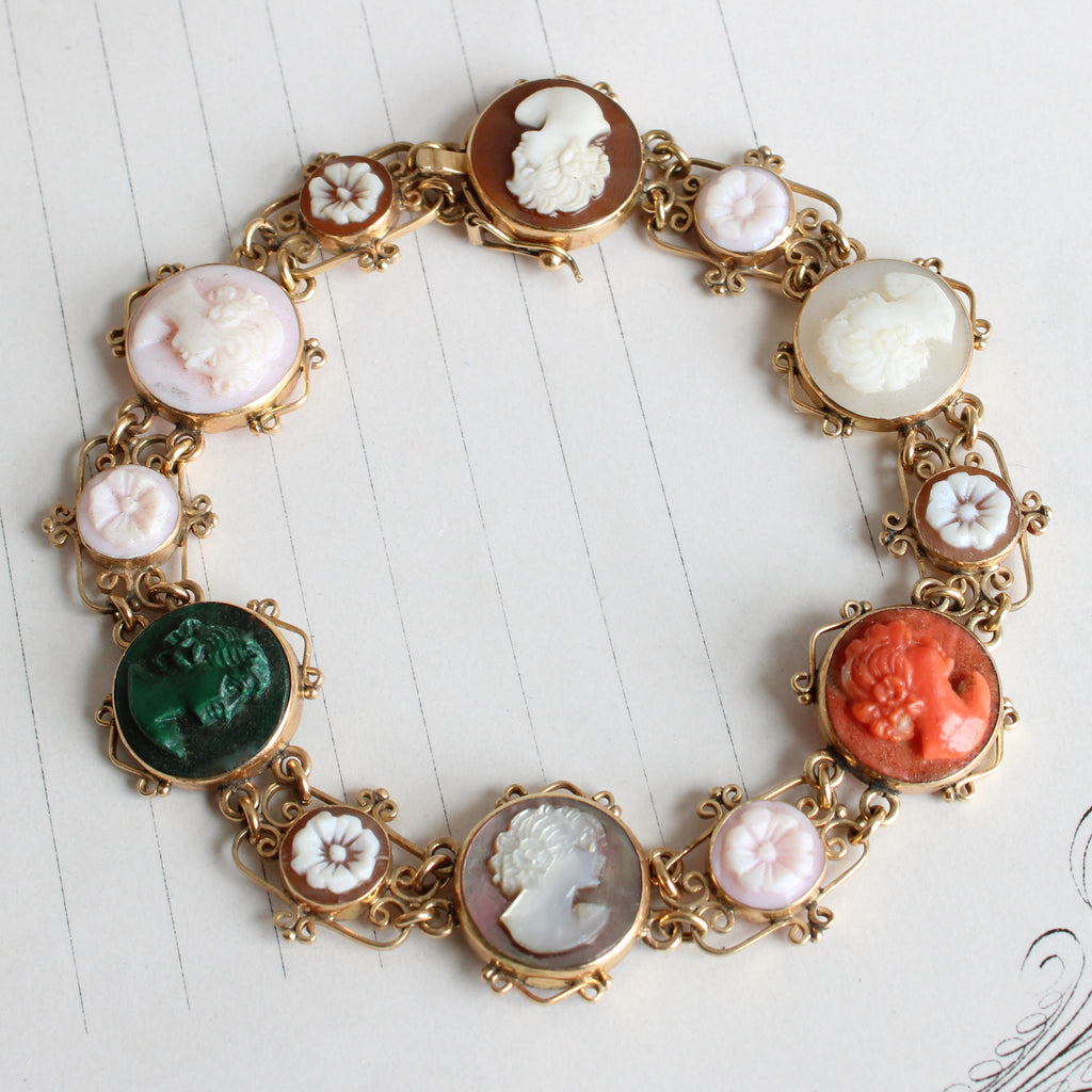 a yellow gold bracelet with cameos carved in coral, malachite, shell and mother of pearl with scrolled filigree decoration 