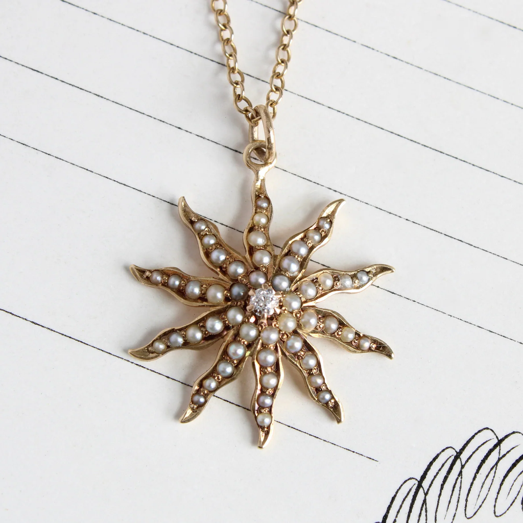 antique yellow gold star charm set with dainty white seed pearls and a diamond in the center.