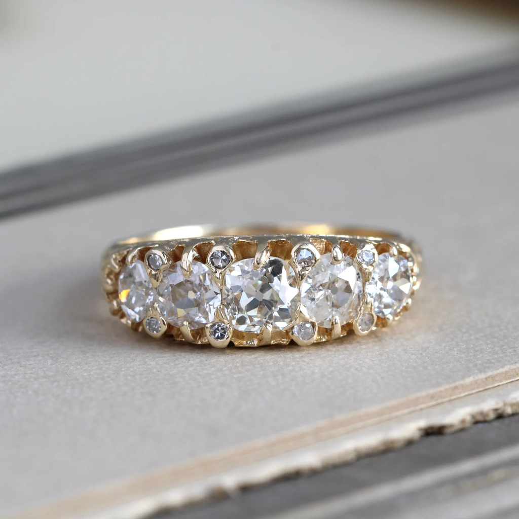 14k yellow gold ring with 5 old mine cut round diamonds offset with smaller diamonds in between the stones.
