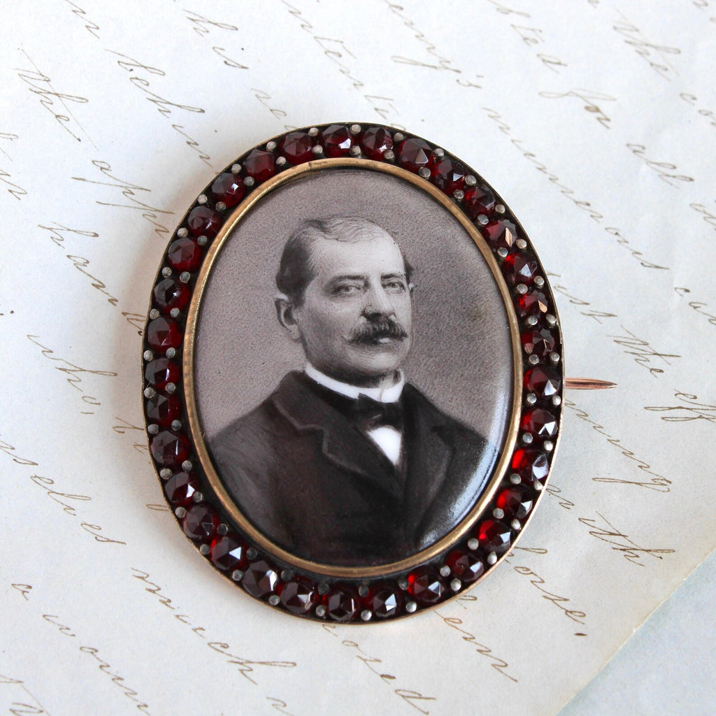 Antique brooch with a black and white portrait of a man in a bezel set with garnet s