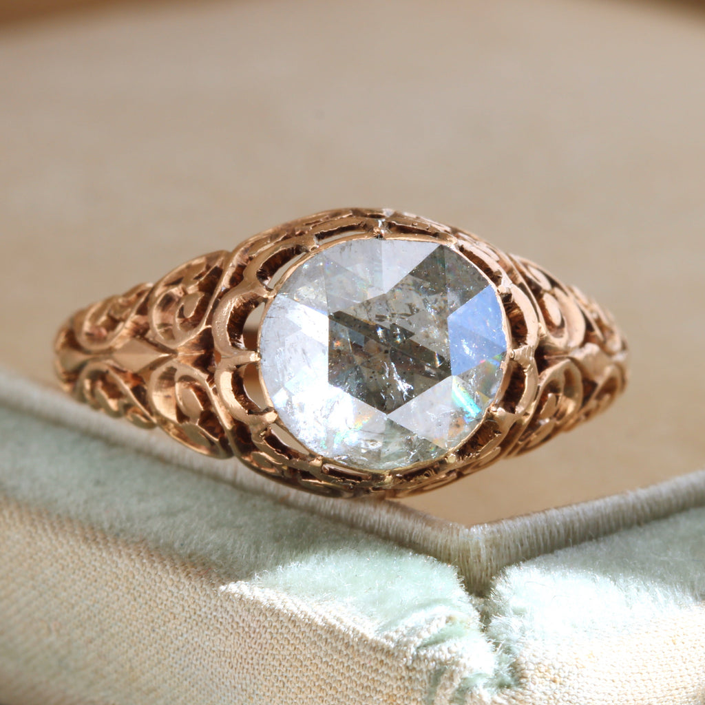 rose gold ring in a cut out filigree style with a large round rose cut diamond