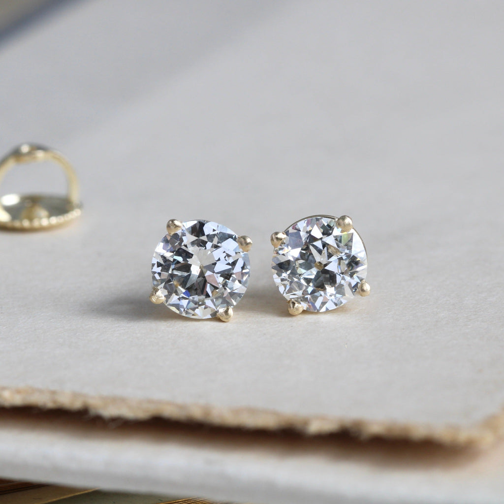 a pair of bright white diamond stud earrings in yellow gold 4-prong settings