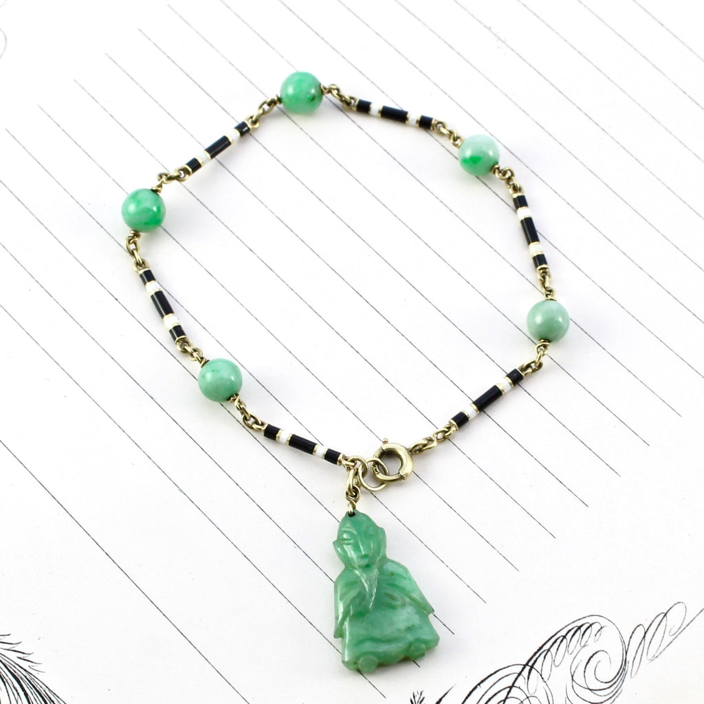 Antique black, white, and green jade beaded bracelet with a carved jade buddha charm hanging from a yellow gold clasp.