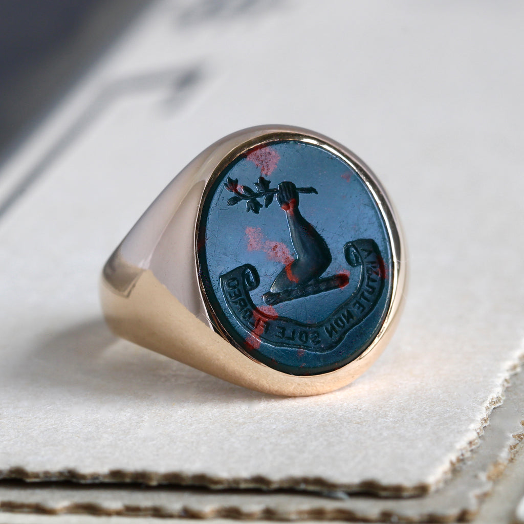 Antique yellow gold intaglio ring with bloodstone carved with a raised arm holding a flower branch.