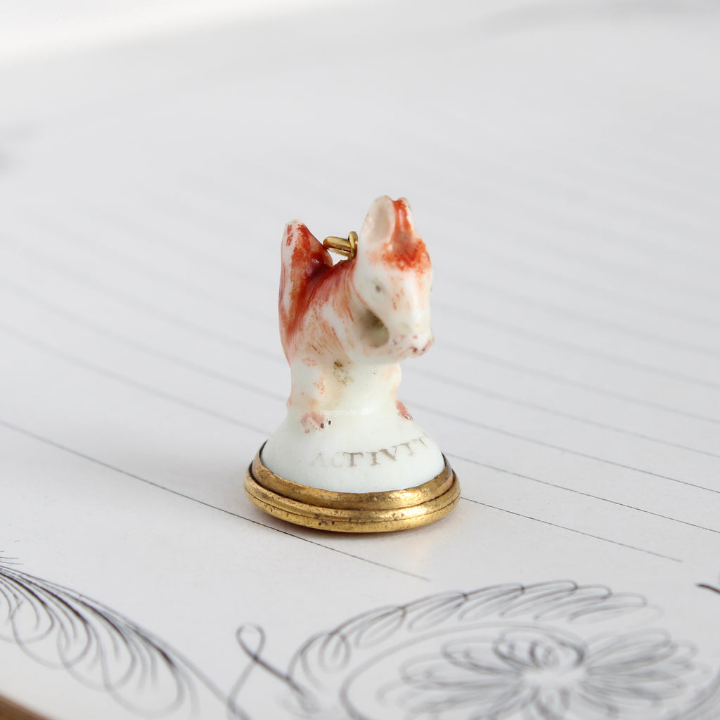 Antique porcelain squirrel fob painted with white and orange paint and yellow gold base and bail.