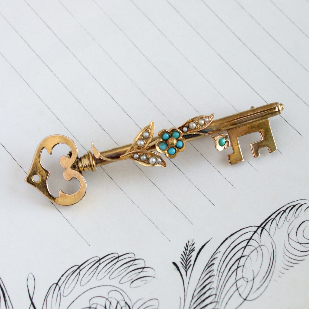 Antique Yellow gold key brooch with a flower set with tiny turquoise and pearl cabochons.