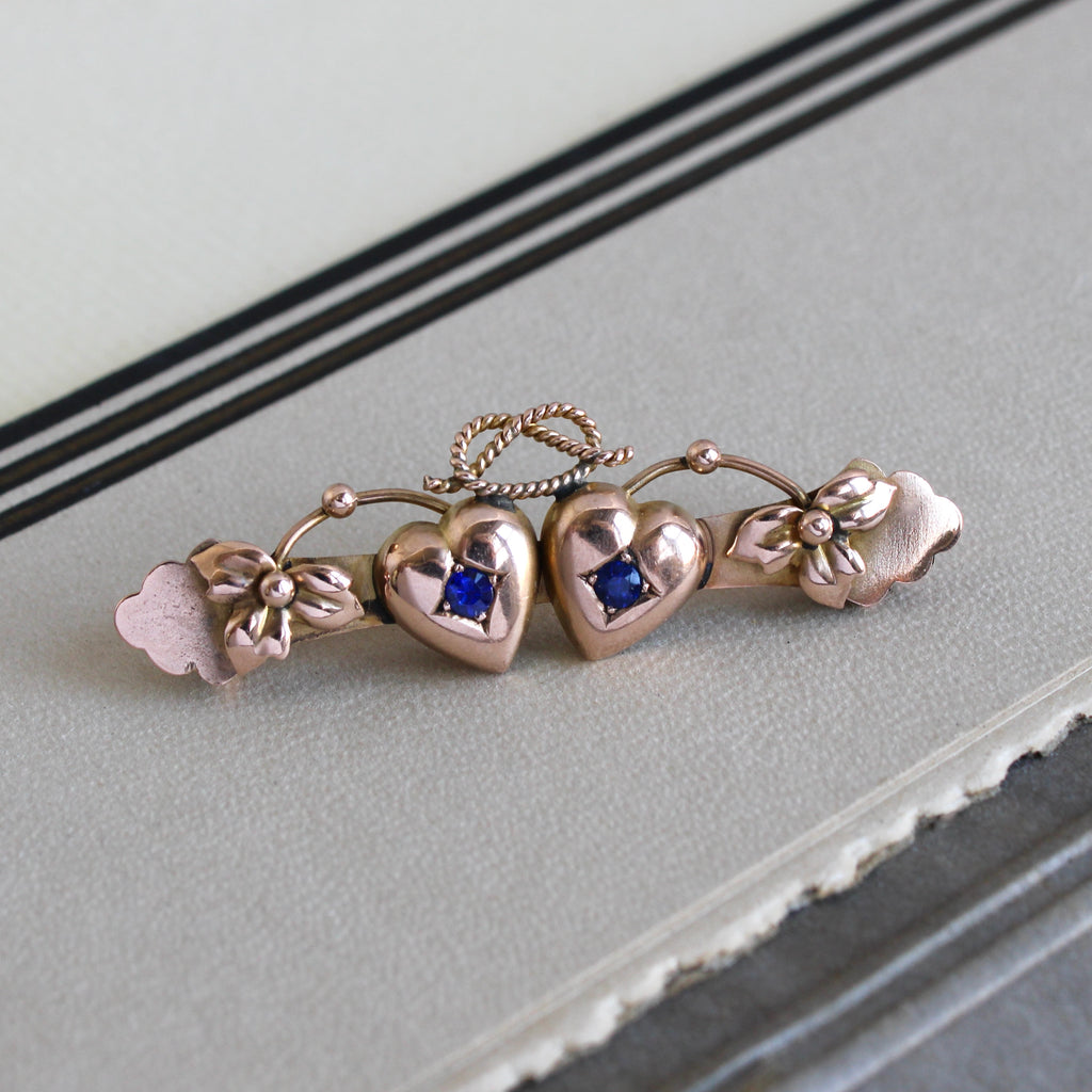 antique rose gold brooch with two hearts side by side with blue sapphire paste.