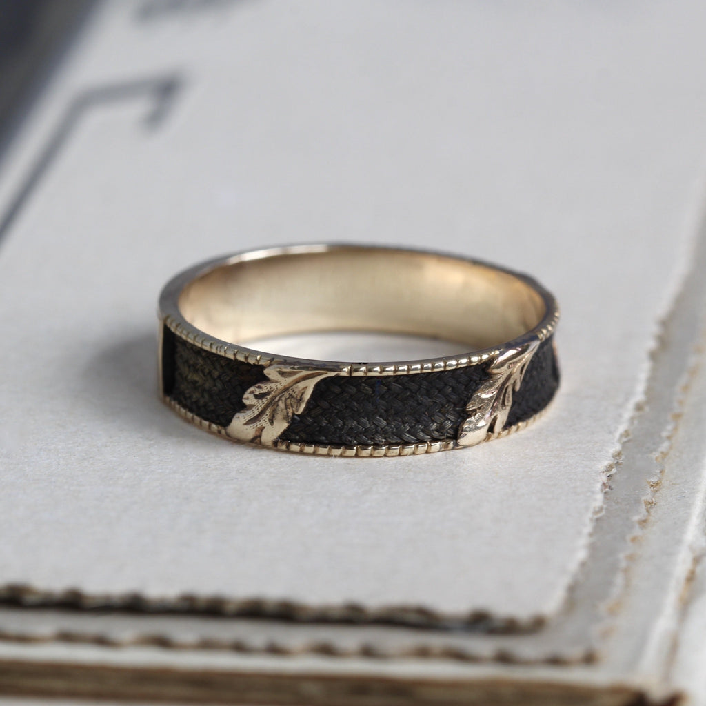 Antique yellow gold ring with woven hairwork inlay along the band with carved gold leaves.