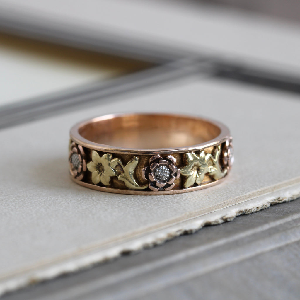 Vintage three tone wedding band with a yellow gold band and green and rose gold flowers.