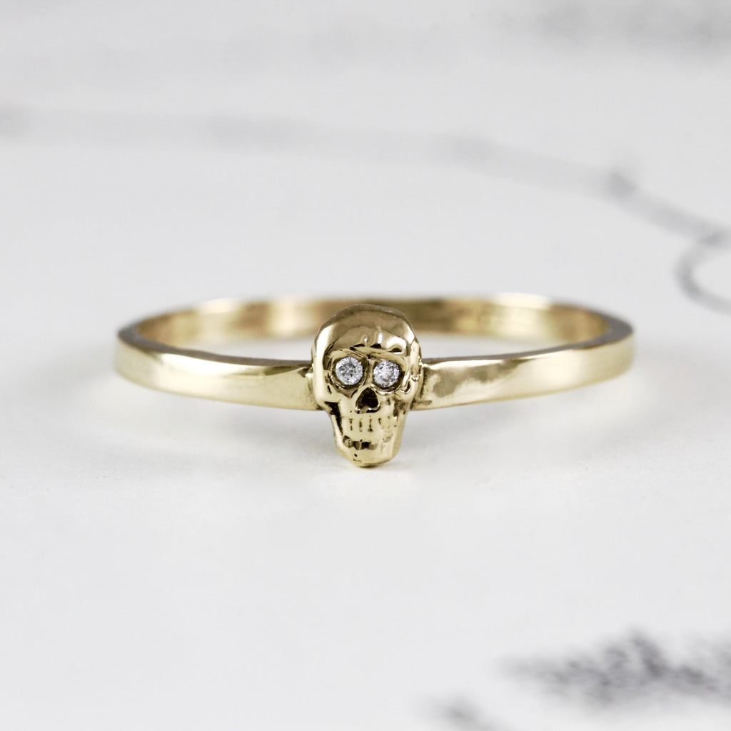 handmade yellow gold ring with a thin gold band with a skull with diamond eyes.