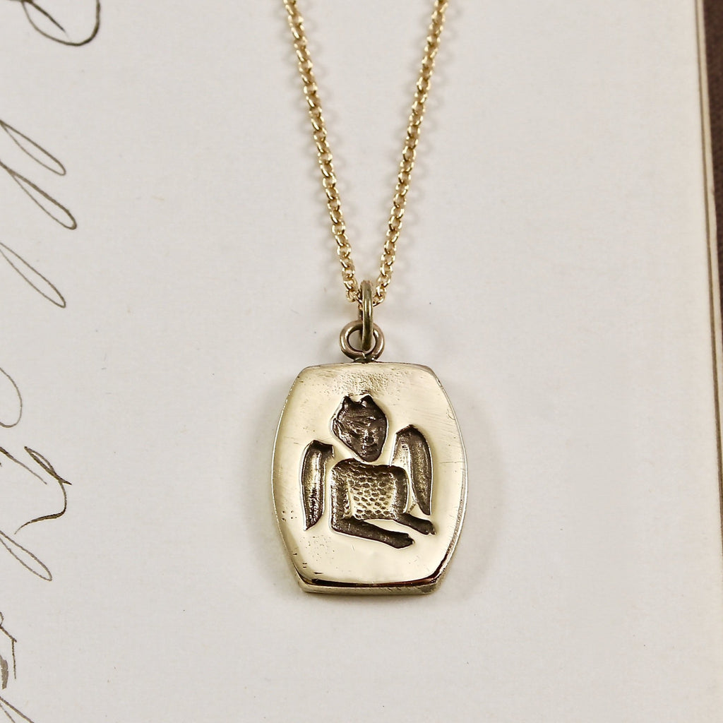 Handmade yellow gold pendant with a depiction of a devil engraved on the front and hangs on a gold cable link chain necklace.