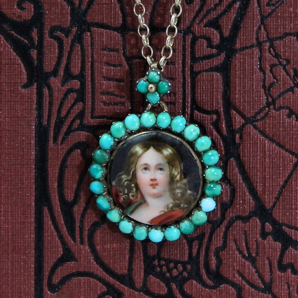 Antique sterling silver round pendant painted with a woman&#39;s protrait framed by a halo of turquoise cabochons, hanging on a silver cable link chain.