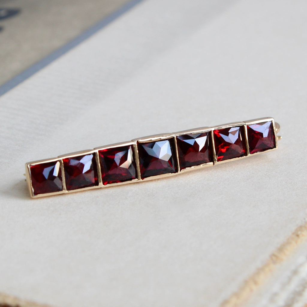 Antique yellow gold brooch set with a line of square faceted red garnets.